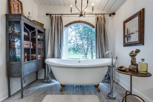 bathroom featuring hardwood / wood-style floors, lofted ceiling, and a notable chandelier