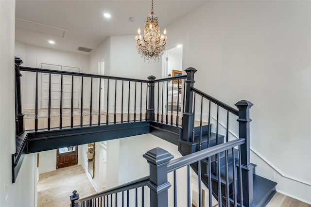 staircase featuring a chandelier and light hardwood / wood-style flooring