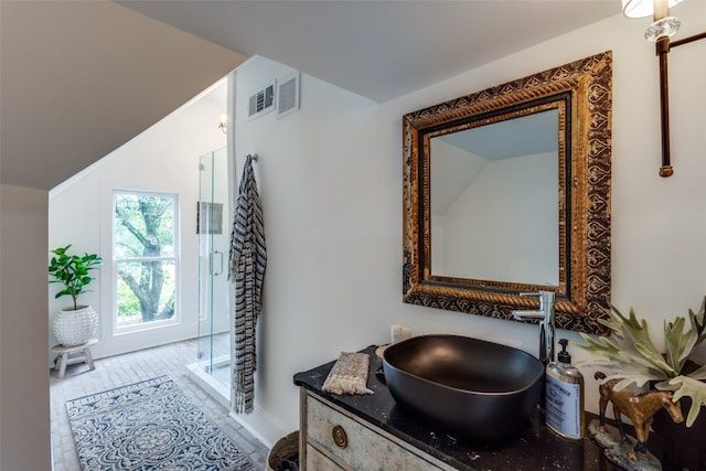 bathroom featuring a shower with shower door, vanity, and lofted ceiling