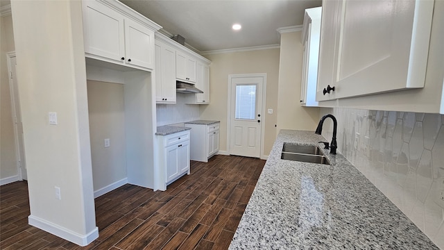 kitchen featuring white cabinets, ornamental molding, sink, dark hardwood / wood-style floors, and light stone countertops