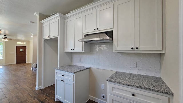 kitchen featuring ceiling fan, backsplash, dark wood-type flooring, white cabinetry, and light stone countertops