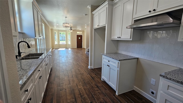 kitchen with hanging light fixtures, white cabinetry, sink, and dark hardwood / wood-style flooring