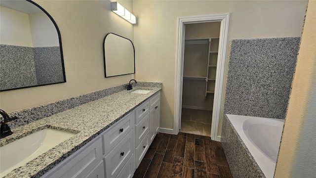 bathroom with tiled tub, vanity, and hardwood / wood-style flooring