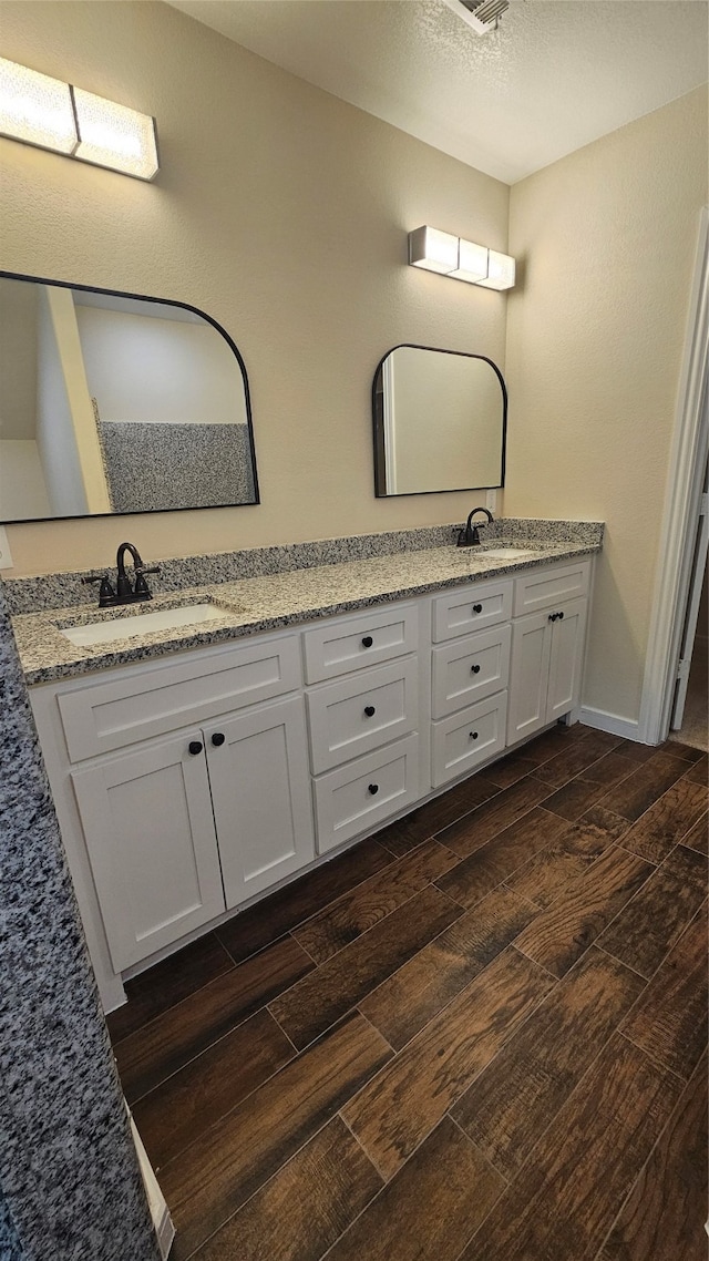 bathroom with wood-type flooring, vanity, and a textured ceiling