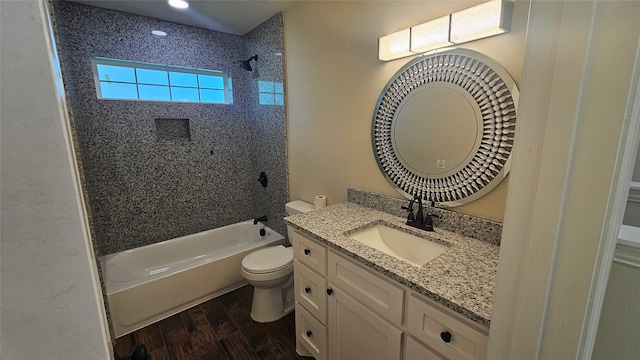 full bathroom featuring tiled shower / bath combo, hardwood / wood-style flooring, vanity, and toilet