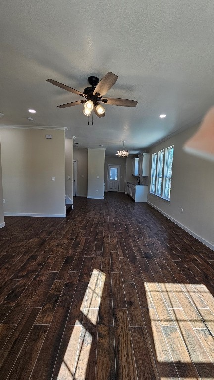 unfurnished living room with dark wood-type flooring, ceiling fan with notable chandelier, and a textured ceiling