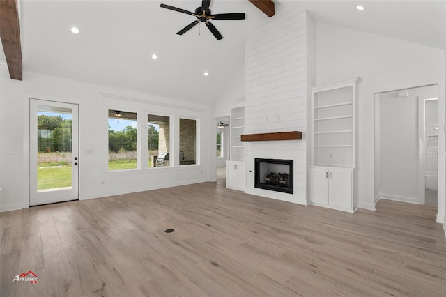 unfurnished living room with ceiling fan, beam ceiling, light hardwood / wood-style floors, and a large fireplace