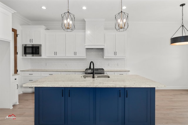 kitchen with decorative light fixtures, light hardwood / wood-style floors, and stainless steel microwave