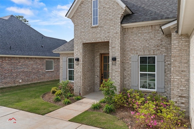 view of exterior entry featuring a lawn