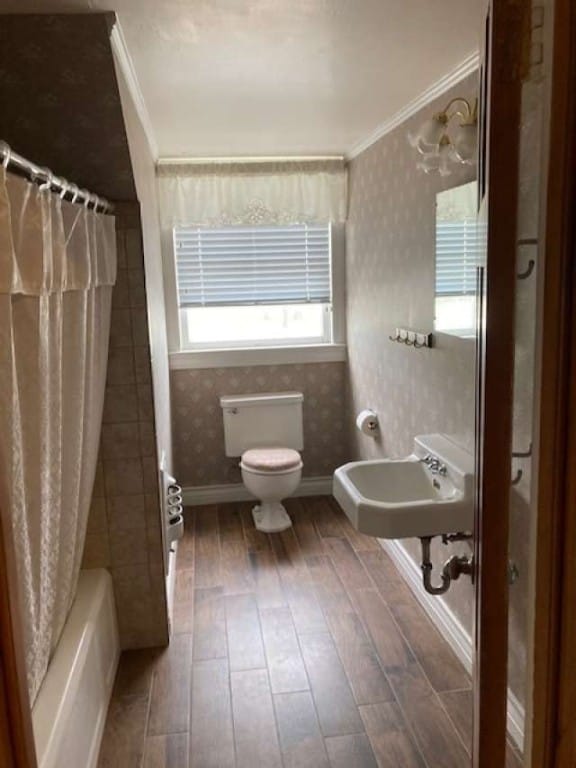 bathroom featuring toilet, shower / bath combination with curtain, and crown molding