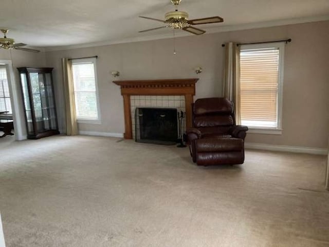 unfurnished living room featuring ceiling fan, a tiled fireplace, light carpet, and crown molding