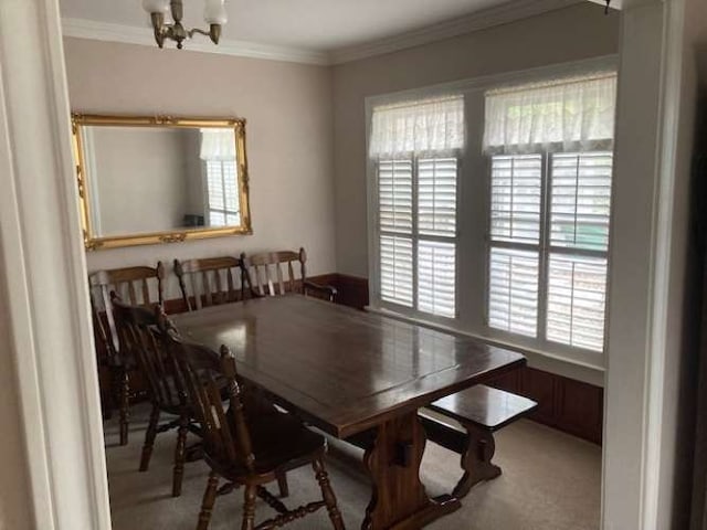 carpeted dining space with a chandelier and crown molding