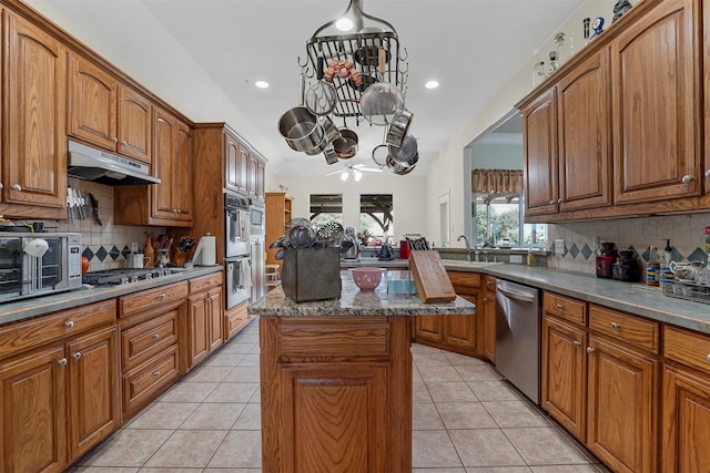 kitchen featuring backsplash, stainless steel appliances, a kitchen island, and light tile patterned flooring