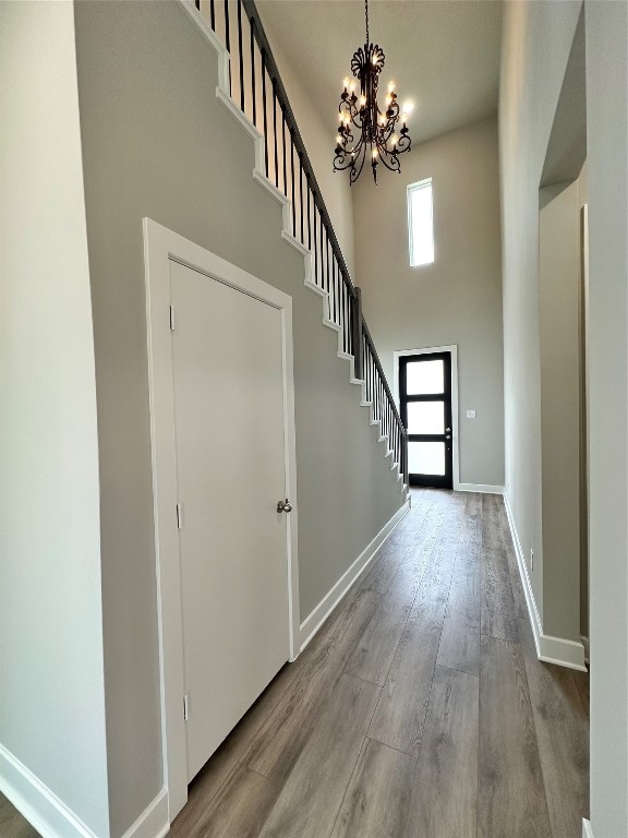 foyer with wood-type flooring, a notable chandelier, and a towering ceiling