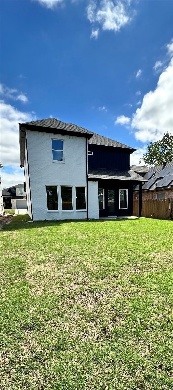 back of house featuring solar panels and a lawn