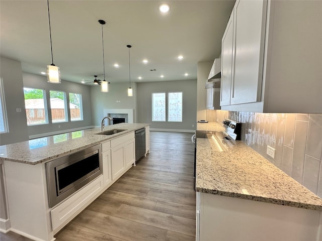 kitchen featuring stainless steel appliances, tasteful backsplash, and a center island with sink