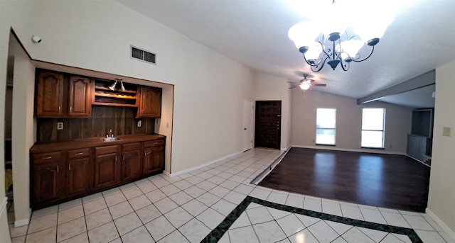 foyer with vaulted ceiling, light tile floors, sink, and ceiling fan with notable chandelier