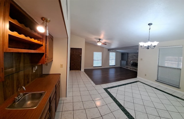 kitchen featuring decorative light fixtures, light tile floors, ceiling fan with notable chandelier, lofted ceiling, and sink