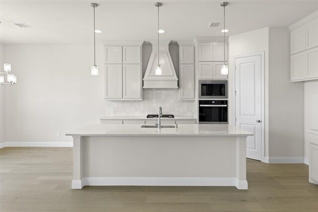 kitchen with premium range hood, light hardwood / wood-style floors, oven, and stainless steel microwave