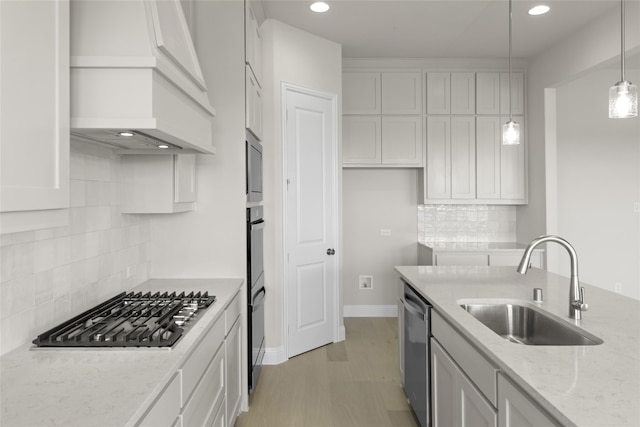 kitchen featuring backsplash, hanging light fixtures, light wood-type flooring, and premium range hood