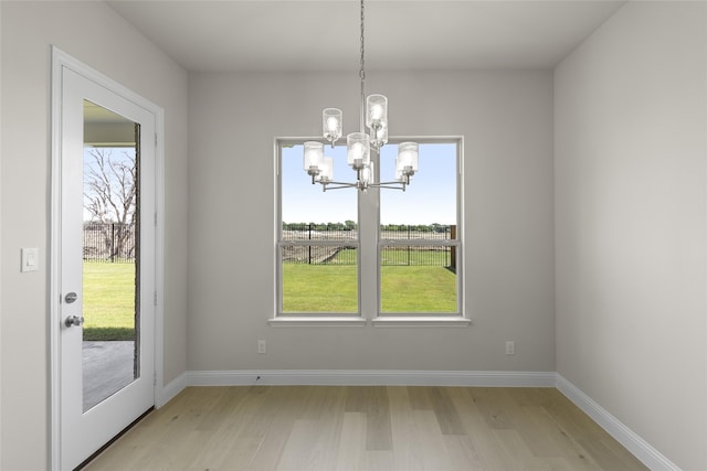 unfurnished dining area with an inviting chandelier and light hardwood / wood-style flooring