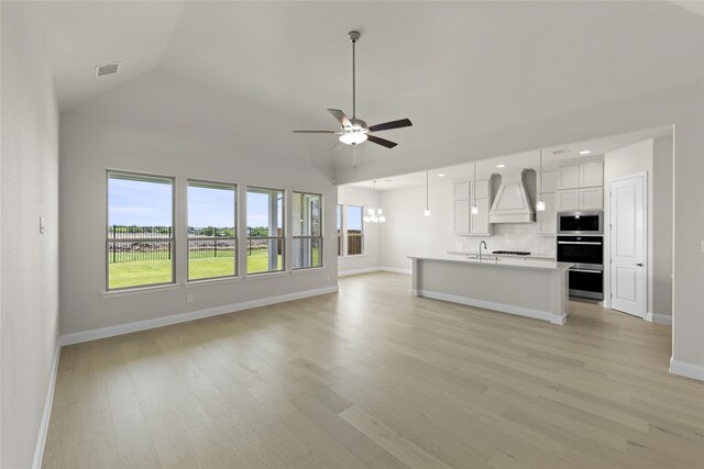 unfurnished living room featuring ceiling fan, sink, light hardwood / wood-style flooring, and lofted ceiling