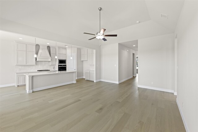 unfurnished living room with ceiling fan, light hardwood / wood-style floors, lofted ceiling, and sink