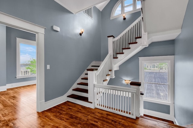 staircase featuring a towering ceiling and dark hardwood / wood-style floors