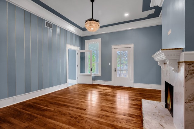 unfurnished living room with an inviting chandelier, a high end fireplace, dark hardwood / wood-style flooring, and ornamental molding