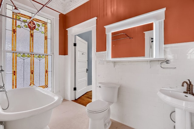 bathroom featuring a bath to relax in, wood-type flooring, toilet, and tile walls