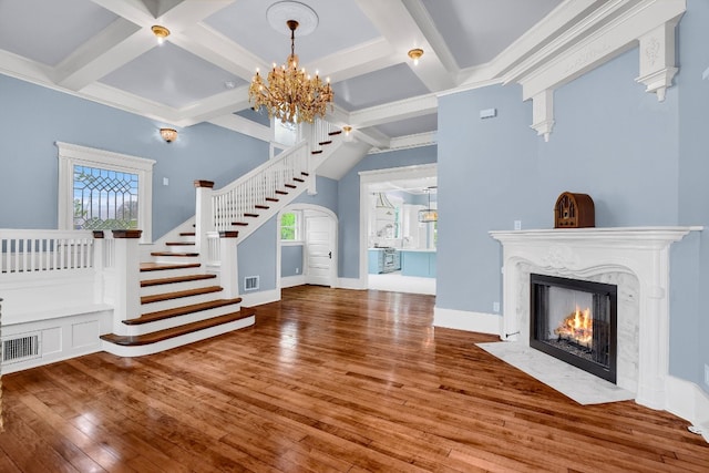 unfurnished living room with a premium fireplace, hardwood / wood-style floors, a chandelier, and crown molding