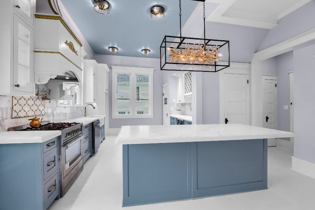 kitchen with decorative light fixtures, a notable chandelier, white cabinets, backsplash, and high end stove