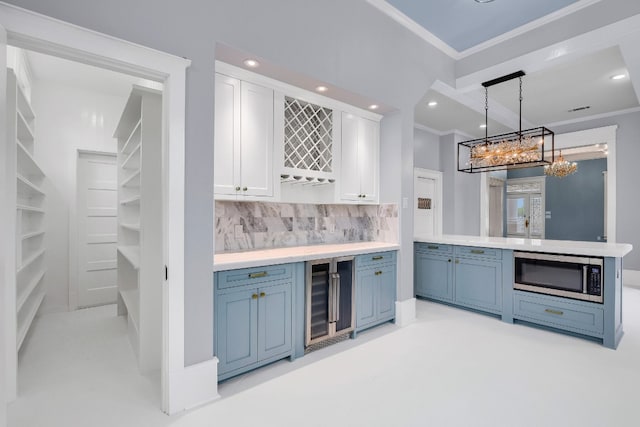 kitchen featuring hanging light fixtures, stainless steel microwave, backsplash, wine cooler, and white cabinetry