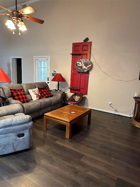 living room with ceiling fan, dark wood-type flooring, and a high ceiling