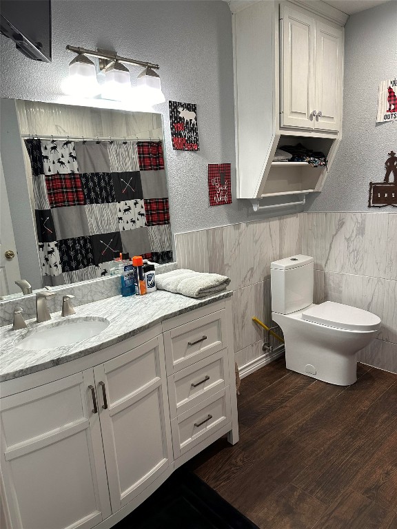 bathroom with vanity, hardwood / wood-style floors, toilet, and tile walls