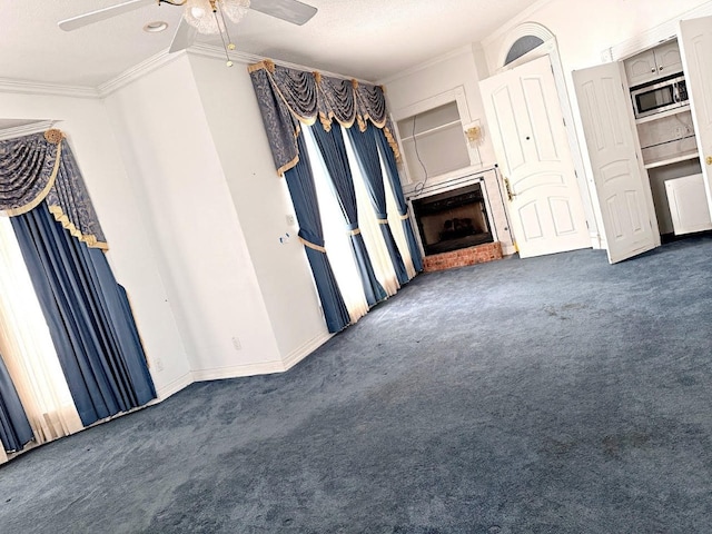 unfurnished living room with a fireplace, dark colored carpet, ceiling fan, and ornamental molding