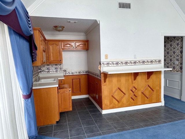 kitchen with dark tile flooring, kitchen peninsula, and sink