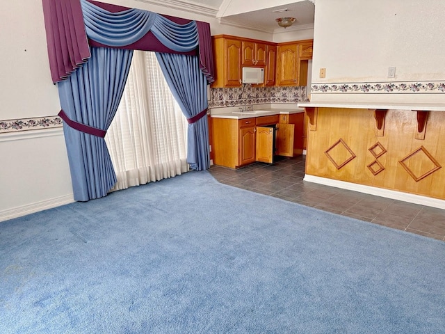 kitchen featuring a breakfast bar area, dark carpet, tasteful backsplash, and ornamental molding