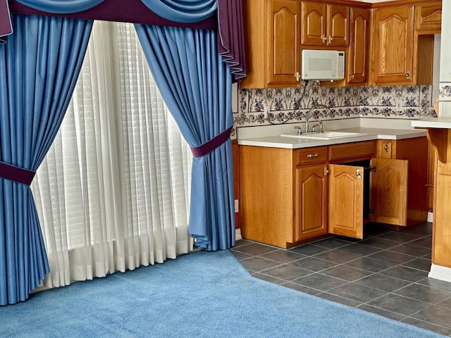 kitchen with tasteful backsplash, sink, and dark colored carpet