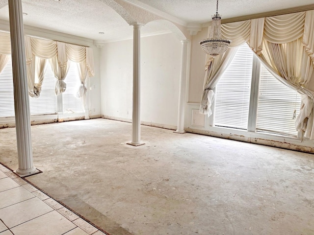 empty room featuring decorative columns, a textured ceiling, and a wealth of natural light