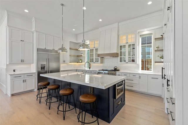 kitchen with a center island with sink, light hardwood / wood-style floors, white cabinetry, and stainless steel appliances