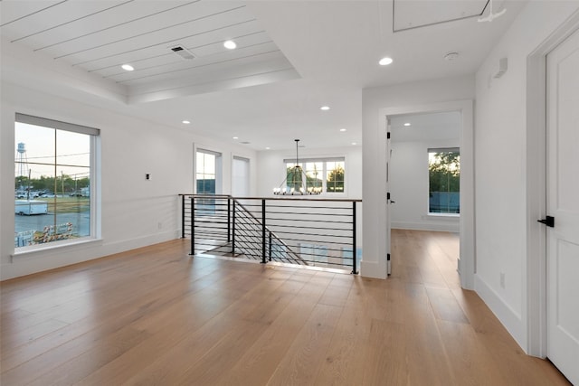 interior space with an inviting chandelier, light wood-type flooring, and a raised ceiling