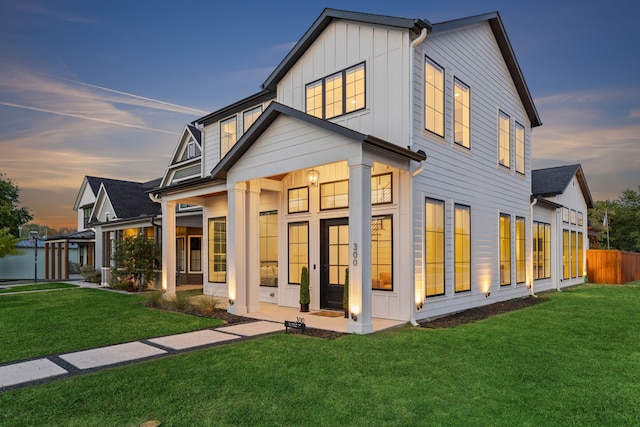 back house at dusk with a lawn