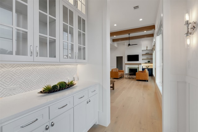 bar with light hardwood / wood-style floors, light stone counters, white cabinets, backsplash, and beamed ceiling