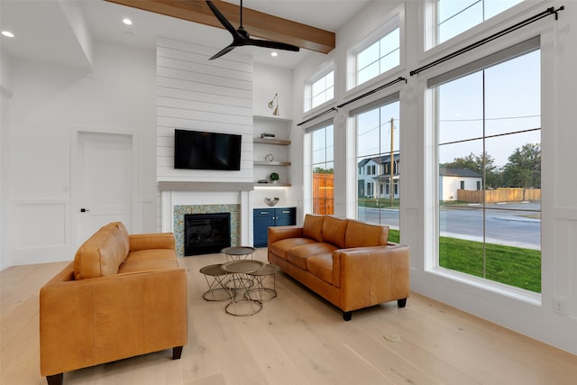 living room with light hardwood / wood-style floors, a towering ceiling, ceiling fan, and plenty of natural light