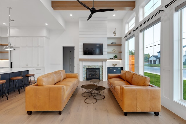 living room with beam ceiling, ceiling fan, and light hardwood / wood-style flooring