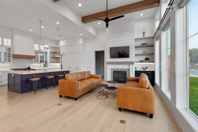 living room with light wood-type flooring, a healthy amount of sunlight, and beamed ceiling