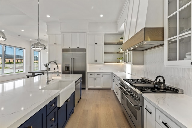 kitchen with light stone counters, high end appliances, white cabinets, hanging light fixtures, and blue cabinets