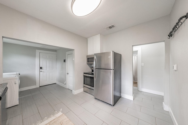 kitchen featuring washing machine and dryer, white cabinetry, and appliances with stainless steel finishes