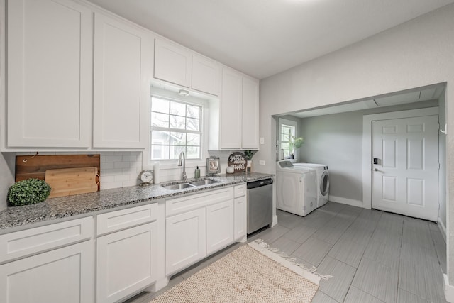 kitchen featuring dishwasher, sink, tasteful backsplash, separate washer and dryer, and white cabinets